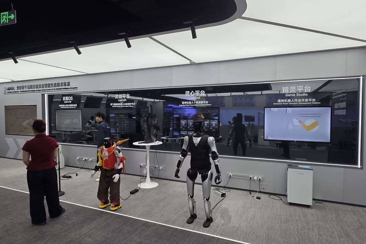 Ein Ausstellungsraum mit Bildschirmwänden und Stehtischen, im Vordergrund mehrere humanoide Roboter zwischen Besuchern.