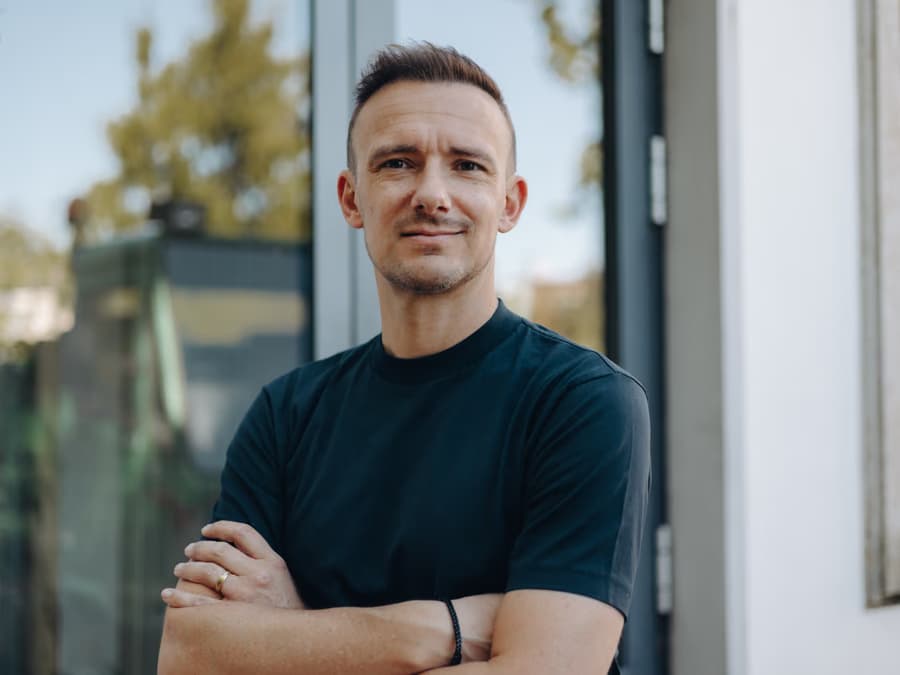 Ein Mitarbeiter des Vertriebsteams vor der Glasfassade des Firmengebäudes.